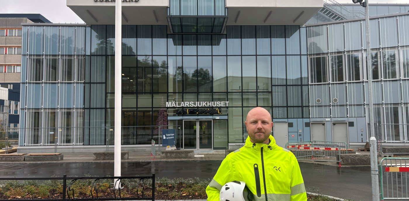 Man i varselkläder står framför sjukhusbyggnad.