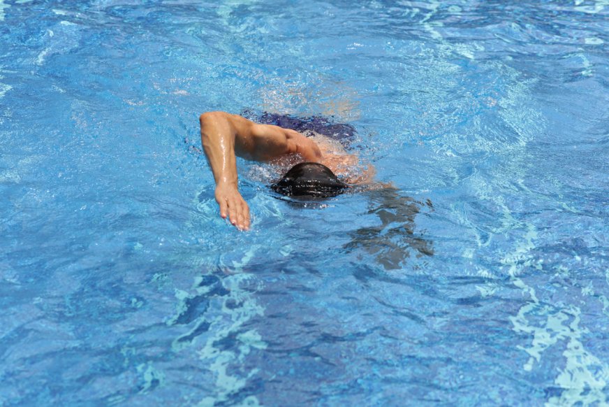 Man som simmar i simbassäng.