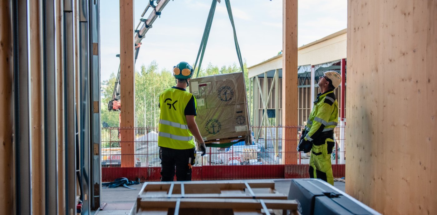 Två byggarbetare i varselvästar på byggarbetsplats.