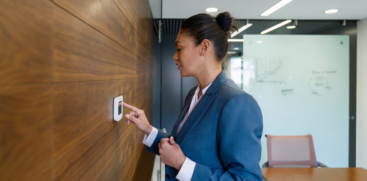 Kvinna i blå kavaj trycker på knapp på väggen.